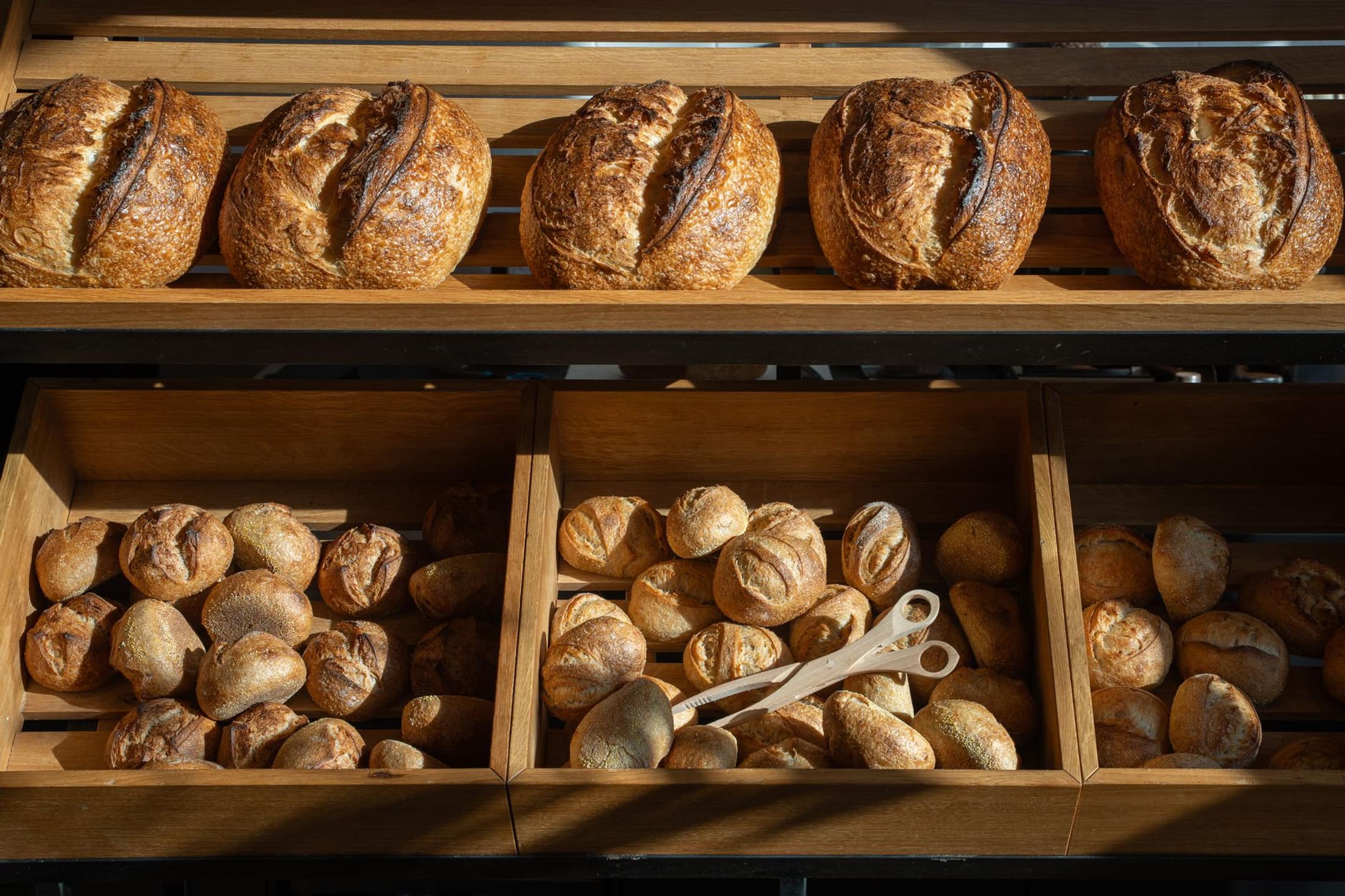Golden loaves of freshly baked bread on wooden bakery shelves